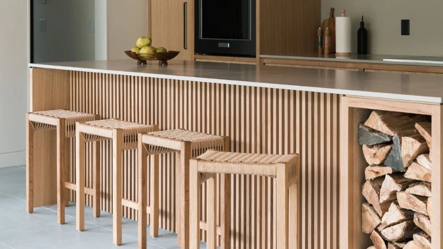 Four white oak Wim stools with woven seats lined up at a kitchen island