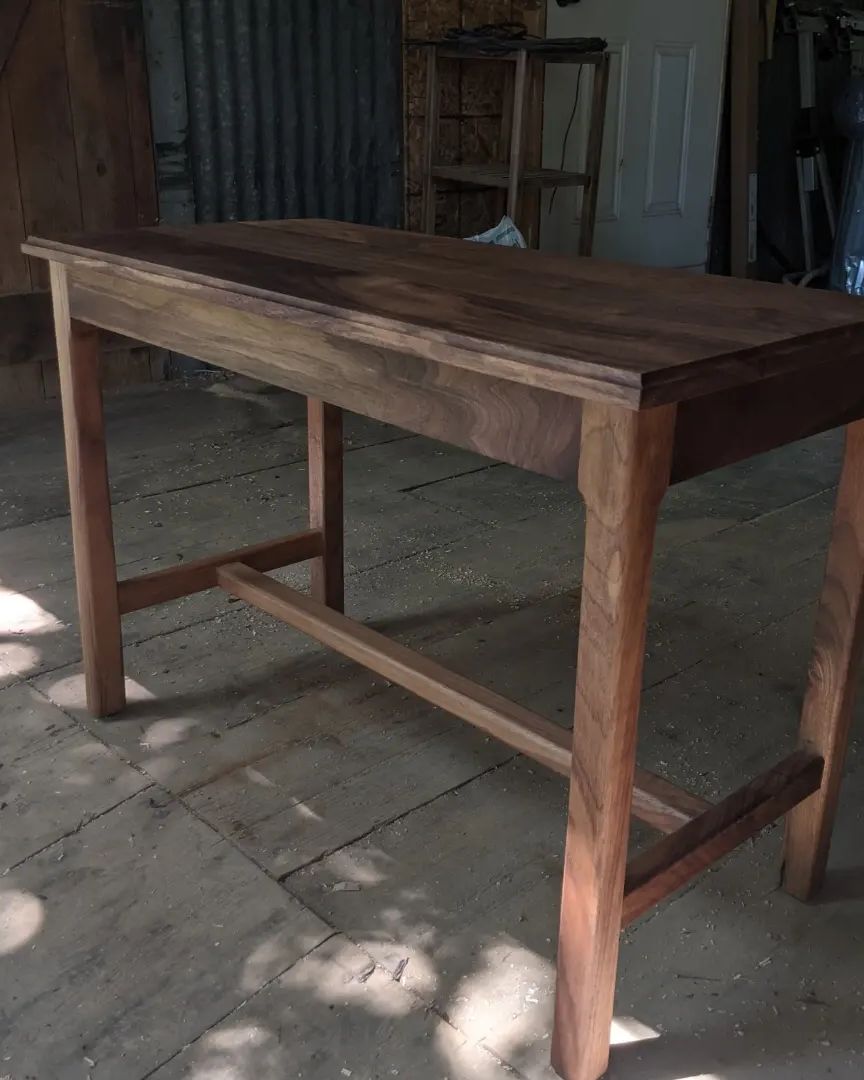 Walnut piano bench standing in dappled light on a barn floor