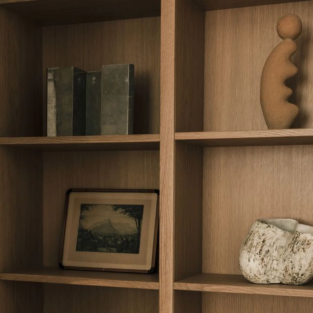 White oak bookcase shelves holding books, a framed print and ceramics