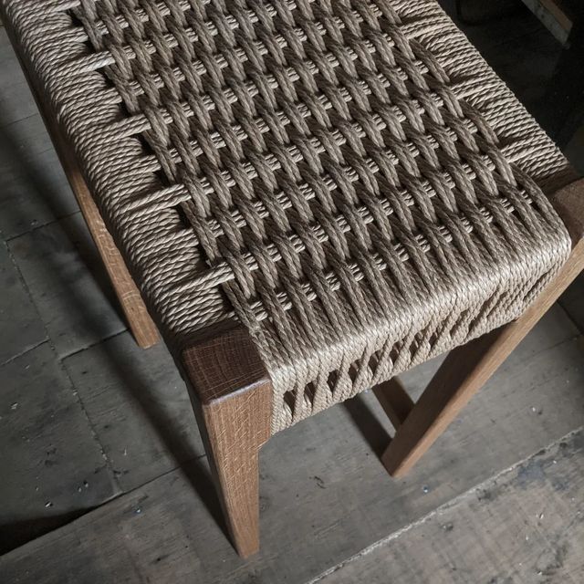 Close-up of a hand-woven cord seat on a hardwood stool